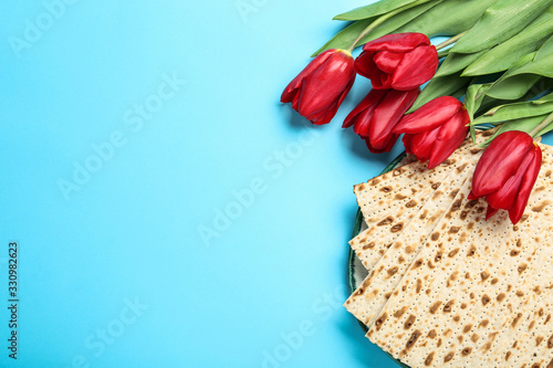 Matzos and flowers on light blue background, flat lay with space for text. Passover (Pesach) Seder