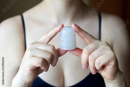 A woman holding a natural deodorant - alunite crystal.