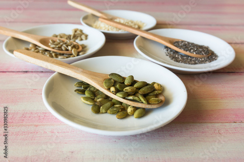 Various seeds in a wooden spoon on a wooden table.