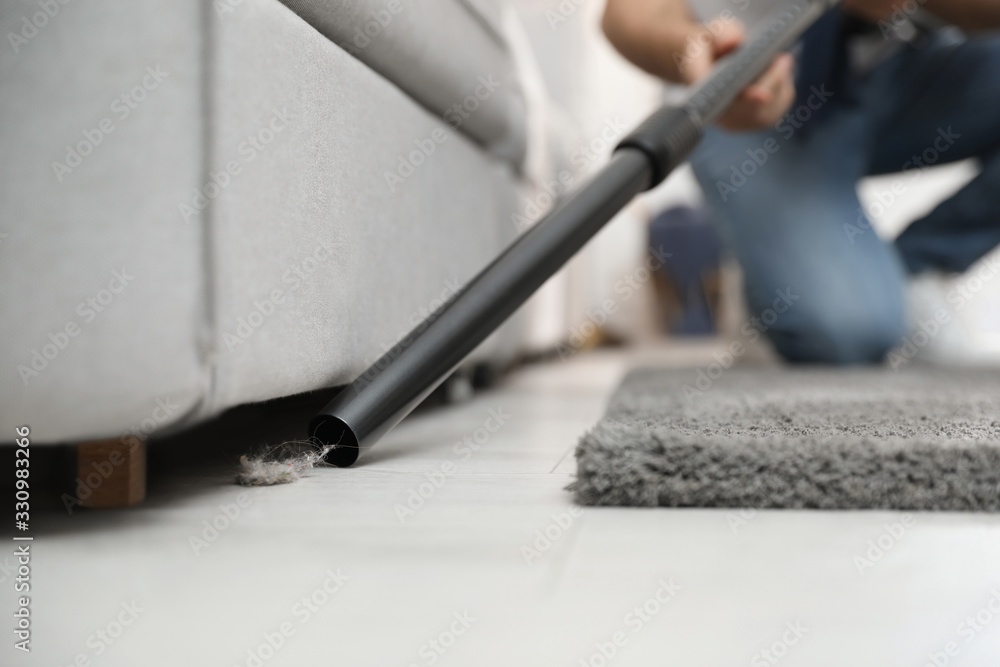 Naklejka premium Young man using vacuum cleaner at home, closeup