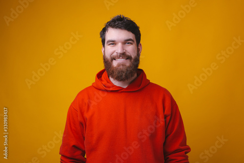 Portrait of smiling bearded hipster man in red blouse looking at the camera