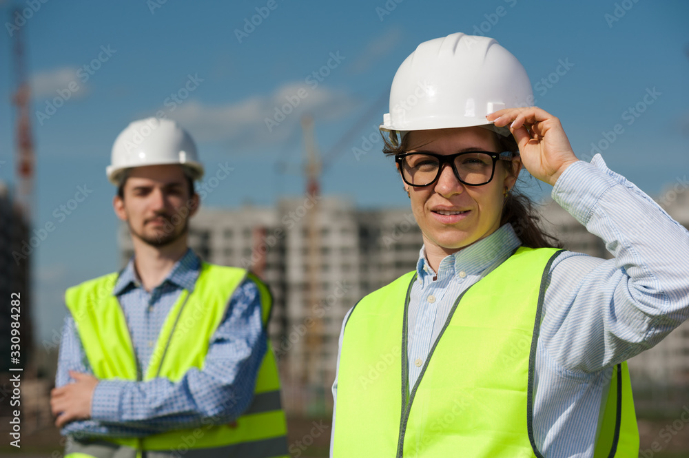 Two Young Engineers Man and Woman In Green Vests And Helmets Two Young Engineers Man and Woman In Green Vests And Helmets