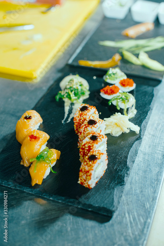 Photo of fresh sushi and rolls in kitchen standing over stone table photo