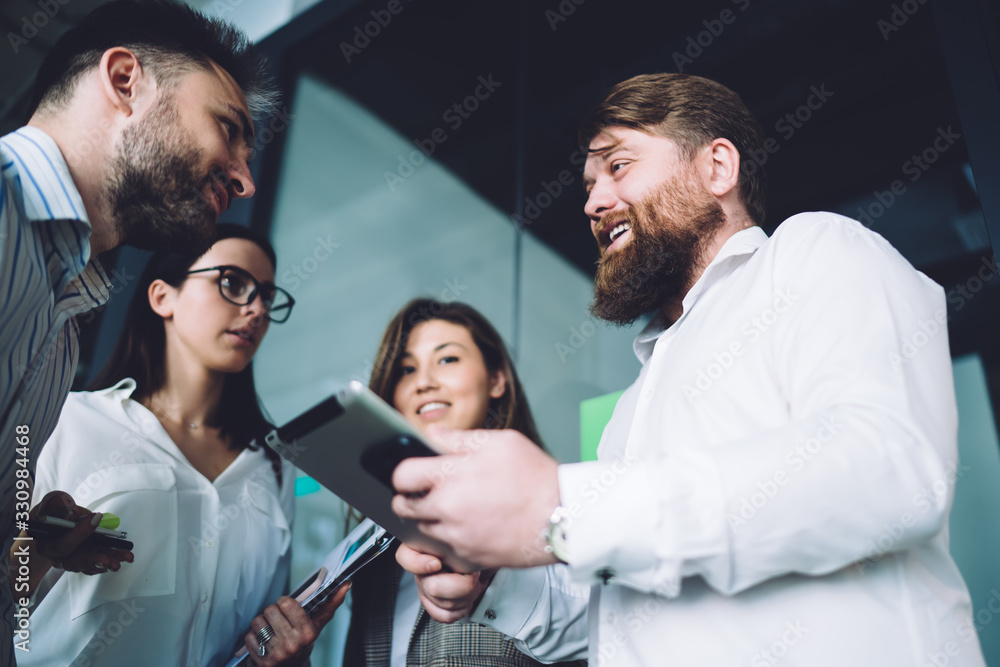Group of office workers having conversation while using tablet