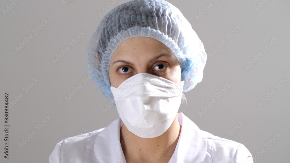 Close-up portrait of face a girl or woman in a protective medical mask. Woman doctor wearing mask and medical hat for hair. The epidemic of influenza virus. Coronavirus or COVID-19. Epidemic situation Close-up portrait of face a girl or woman in a protective medical mask. Woman doctor wearing mask and medical hat for hair. The epidemic of influenza virus. Coronavirus or COVID-19. Epidemic situation