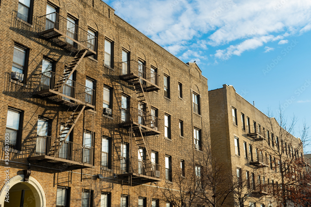 A Row of Old Brick Residential Buildings with Fire Escapes in Astoria Queens of New York City A Row of Old Brick Residential Buildings with Fire Escapes in Astoria Queens of New York City