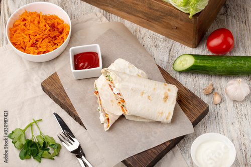 Shawarma served on wooden board with sauces and vegetables photo