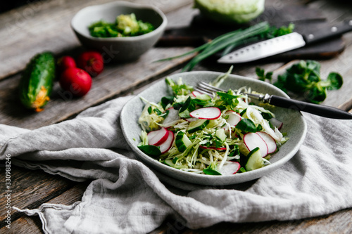 Spring veggie salad with cabbage, radish and cucumbers on a plate