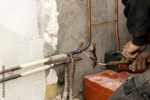 Pipework. Plumbing contractor works sweating the joints on the copper pipe domestic water system photo