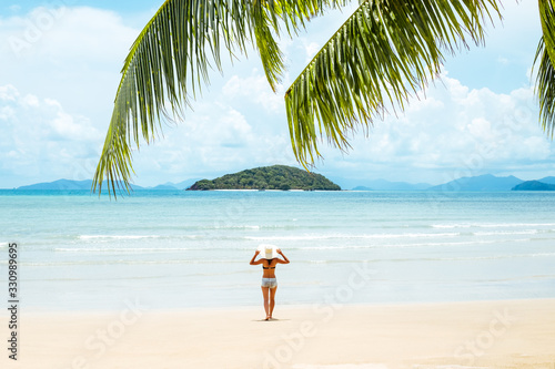 Green palm tree leaf and young woman standing near sea