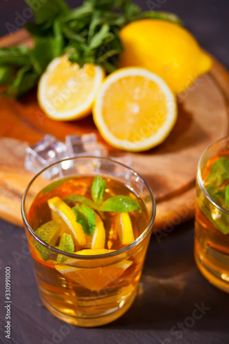 Two glasses of cold refreshment tea with ice and lemon fruit.