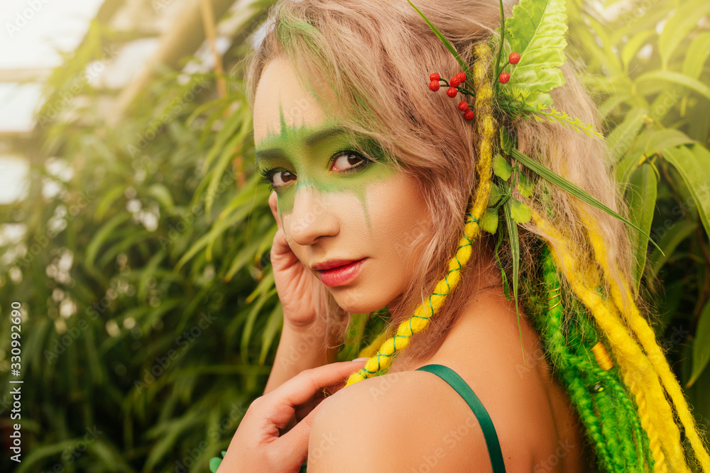 Fototapeta premium Dryad stands among the trees. Portrait of a beautiful girl with makeup on her face. Forest Nymph