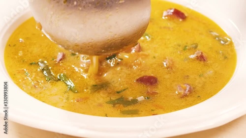 Coursework: the cook pours the meat soup into a plate, slowing down with a large satine.