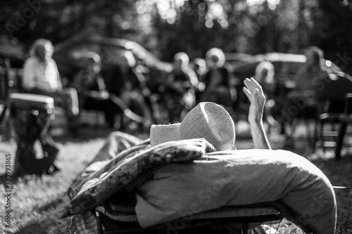 An atmospheric selective focus black and white view from behind an old man at his farewell party during final days of life with blurry family in background. photo