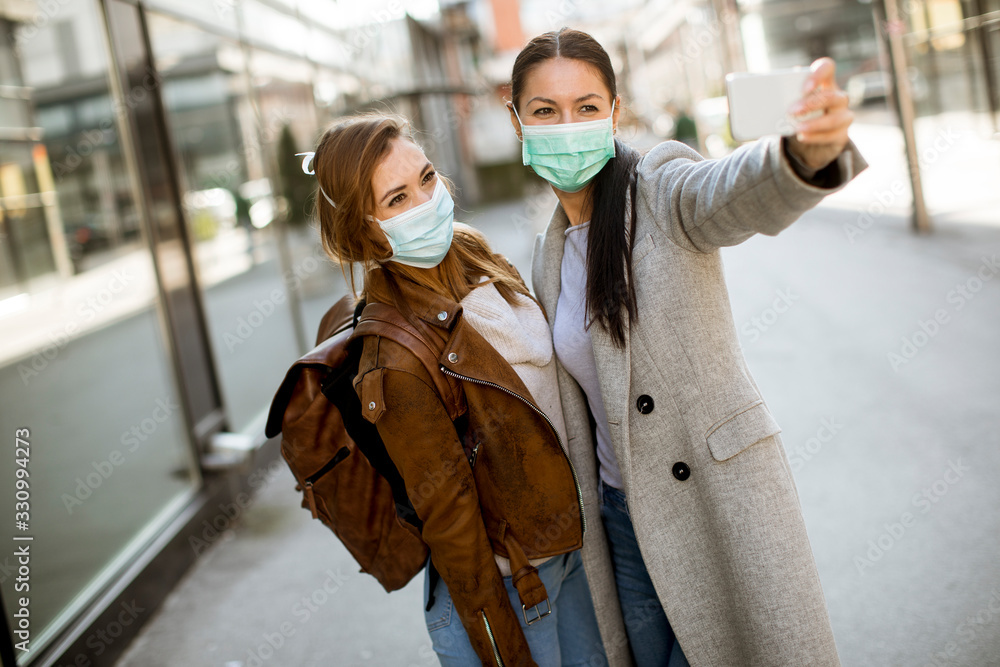 Naklejka premium Pretty young women with protective facial mask on the street