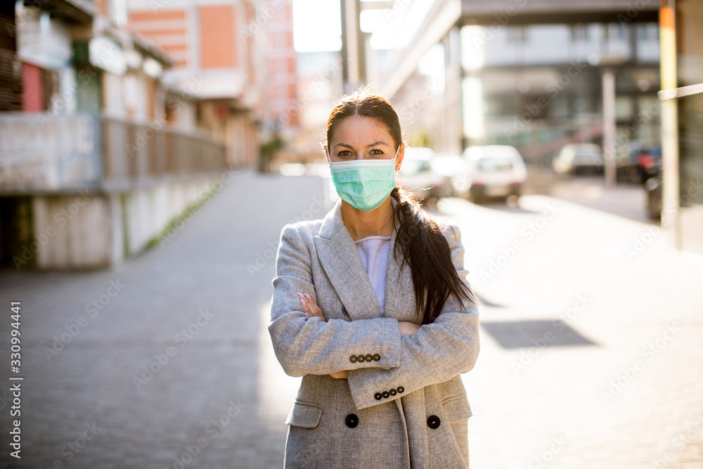 Fototapeta premium Pretty young woman with protective facial mask on the street