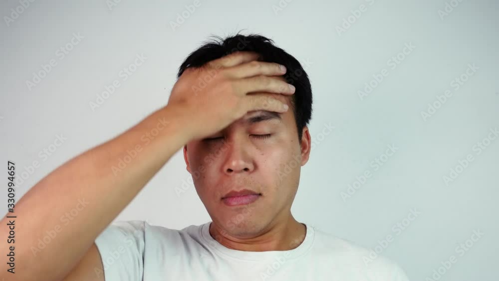 Close up portrait of Serious Asian man closing eyes and rubs his head expressing frustration and stressful over grey background. Emotion and expression concepts. Close up portrait of Serious Asian man closing eyes and rubs his head expressing frustration and stressful over grey background. Emotion and expression concepts.