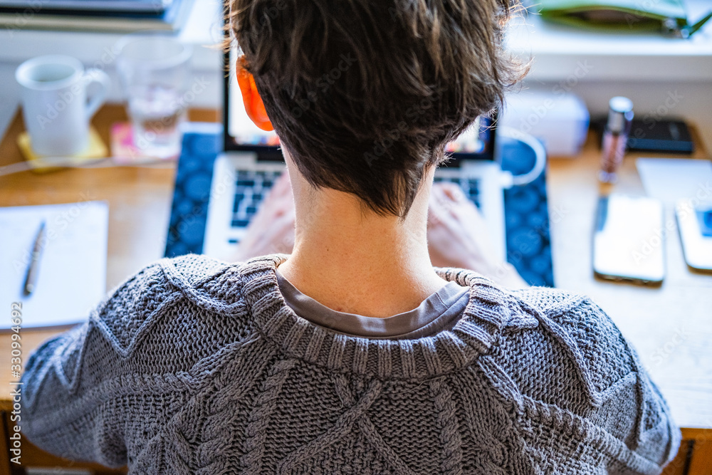 Fototapeta premium Home office work. Young caucasian short hair woman working online from home on computer laptop from back, head and shoulders
