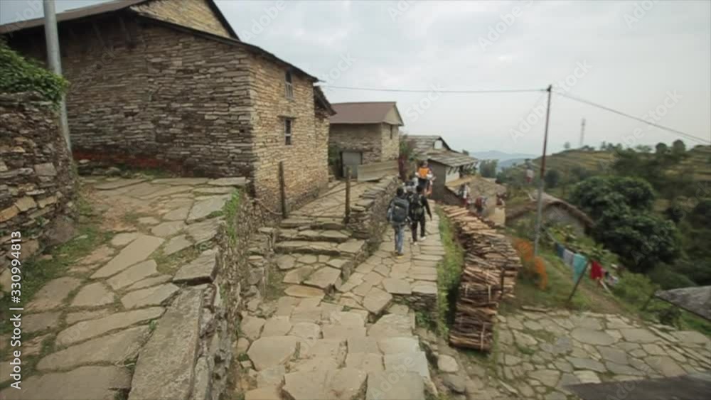 A group of people, tourists walking down a village trail in Nepal. Backpacks. Nepal. Back rear view. A group of people, tourists walking down a village trail in Nepal. Backpacks. Nepal. Back rear view.