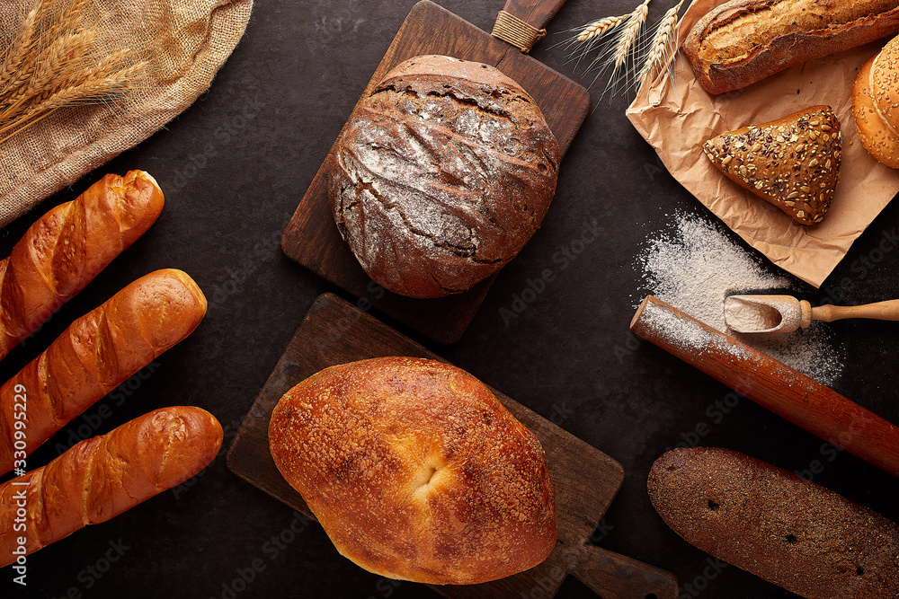 Different bread and bread slices. Spikelets of wheat. Food background. Old vintage cutting boards.