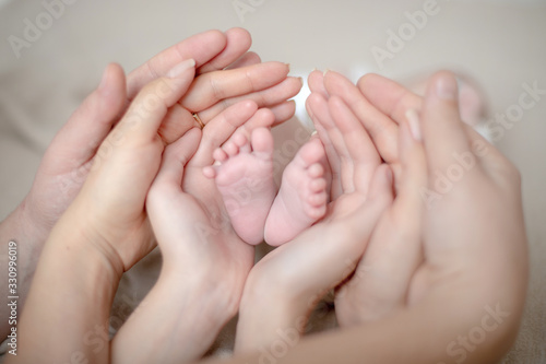 Hands of the family hold the legs of a newborn