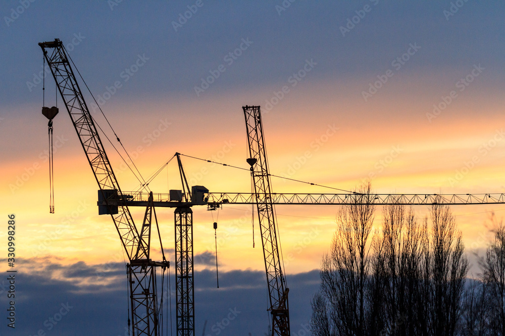 Silhouette of construction crane at sunset. Industrial background