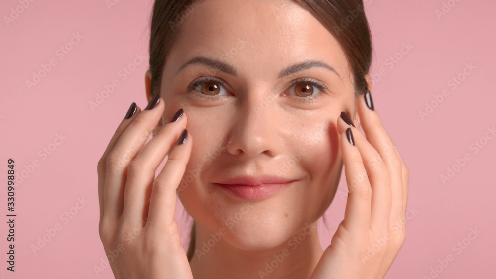 30s brunette woman makes a facial massage and smiling. self-care concept 30s brunette woman makes a facial massage and smiling. self-care concept