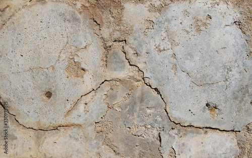 Cracked pieces and falling off gray-white stucco with cracks.