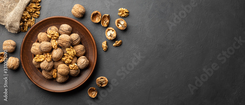Nuts. Walnut kernels and whole walnuts on dark stone table. Black background. Top view, flat lay with copy space.