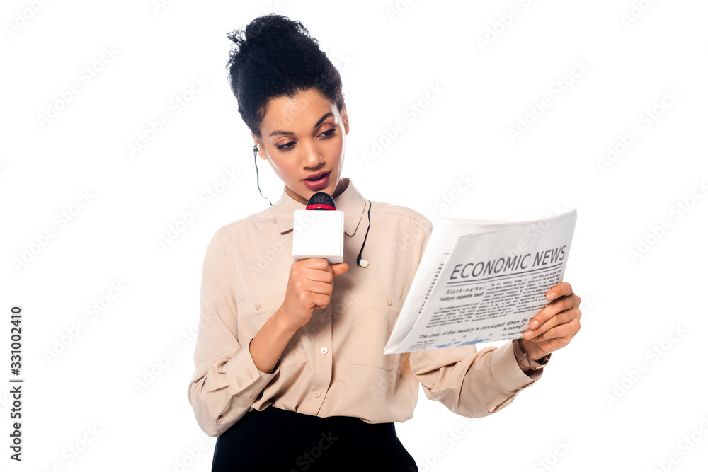 African american journalist speaking into microphone and looking on newspaper with economic news lettering isolated on white African american journalist speaking into microphone and looking on newspaper with economic news lettering isolated on white