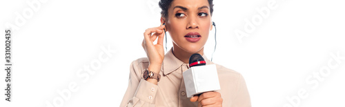 Schilderij op canvas African american journalist with microphone putting headphones in ears isolated