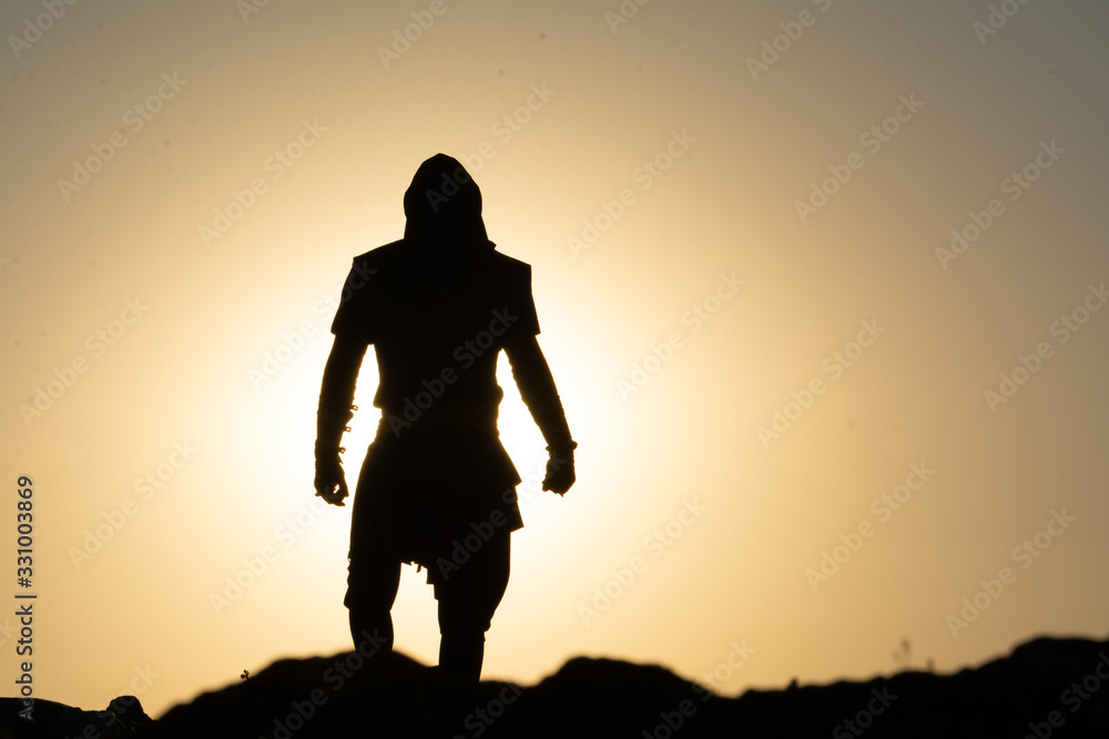 Sillhouette of a Man Standing on a Mountain Peak at the Sunset