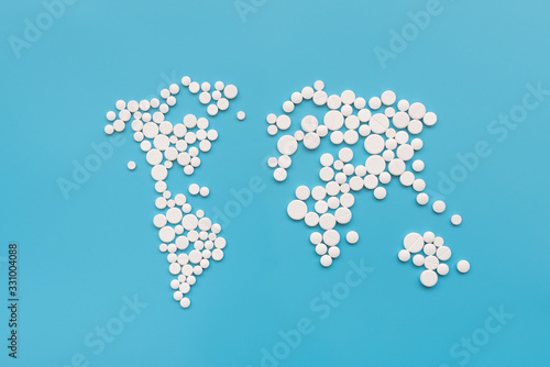 Covid-19. World map shape make from white pills on blue background. Flu, illness concept