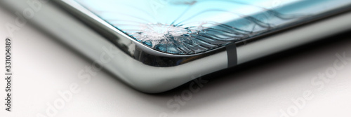 Modern smartphone lying at table with crack in corner