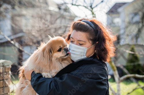 Mature Woman in mask with his pet on street because of air pollution and epidemic in city. Protection against virus, infection.