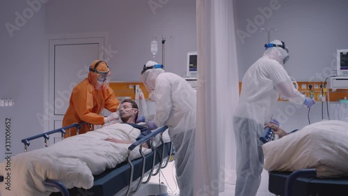 Doctor in Protective Suit Putting on Oxygen Mask on Patient Suffering from Coronavirus - Wide Dolly Shot in Slow Motion