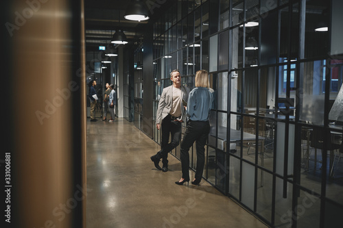 Two businesspeople talking in a hallway after a late meeting