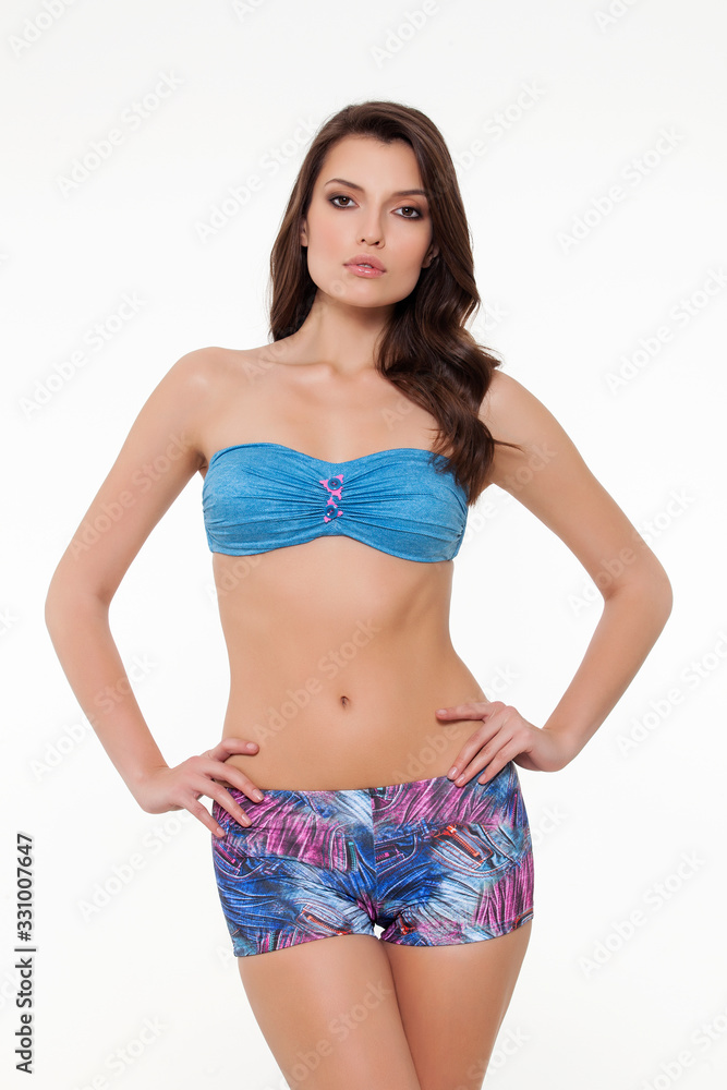 beautiful girl posing in stylish detailed blue and colorful bikini on white background. beautiful girl posing in stylish detailed blue and colorful bikini on white background.