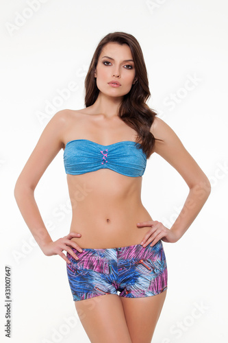 beautiful girl posing in stylish detailed blue and colorful bikini on white background.