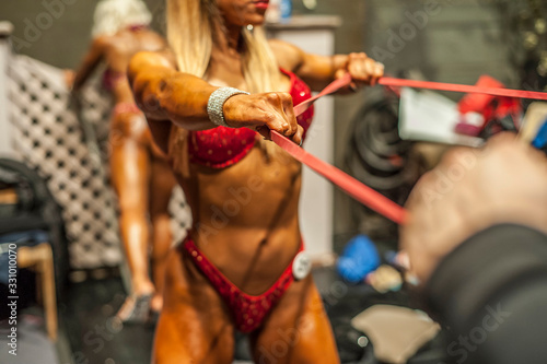 Attractive woman and men at the bodybuilding competition. Strong and muscular bodybuilders before the show