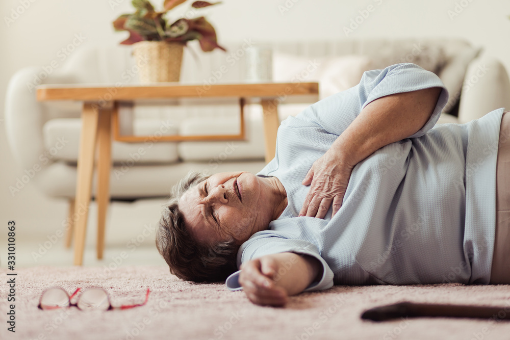Senior woman lying on a floor with a heart attack - obrazy, fototapety, plakaty 