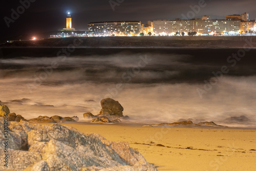 panoramica de la ciudad de la coruña con el faro de  la toore de hercules la fondo y un mar revuelto visto desde la playa de riazon photo