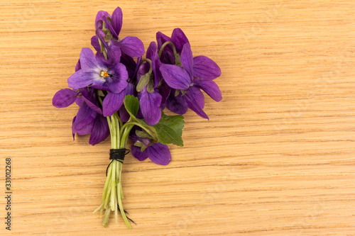 Bouquet of violet flowers (viola odorata) on wooden background, copy space