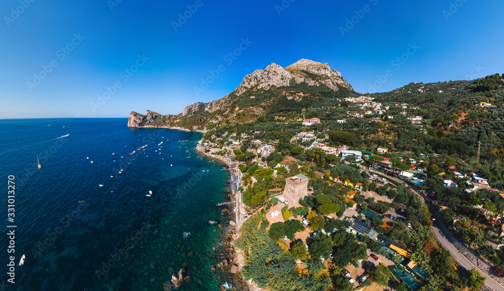 Aerial view of coastline of the village of Nerano. Private and wild beaches of Italy. Turquoise, blue surface of the water. Vacation and travel concept. Boats on raid in bay. Copy space. Summer day