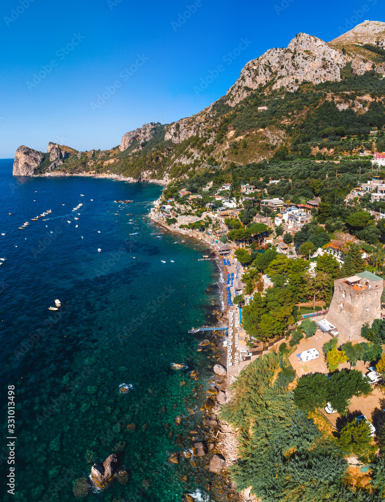 Aerial view of coastline of the village of Nerano. Private and wild beaches of Italy. Turquoise, blue surface of the water. Vacation and travel concept. Boats in bay. Copy space. Vertical photo