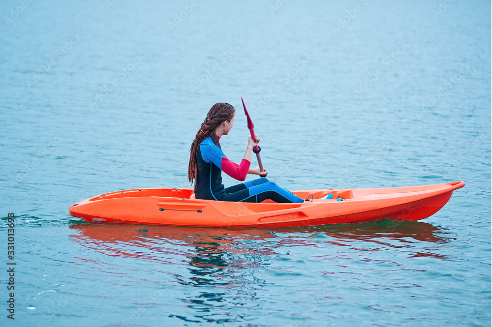 Kayaking. Girl on an orange kayak swims on the lake