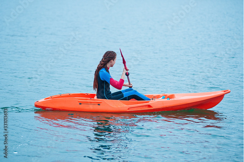 Kayaking. Girl on an orange kayak swims on the lake © marina_li_1