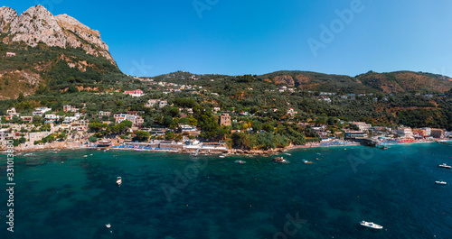 Aerial view of coastline of the village of Nerano. Private and wild beaches of Italy. Turquoise, blue surface of the water. Vacation and travel concept. Boats on raid in bay. Copy space. Summer day