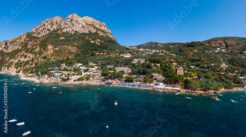 Fototapeta Naklejka Na Ścianę i Meble -  Aerial view of coastline of the village of Nerano. Private and wild beaches of Italy. Turquoise, blue surface of the water. Vacation and travel concept. Boats on raid in bay. Copy space. Summer day