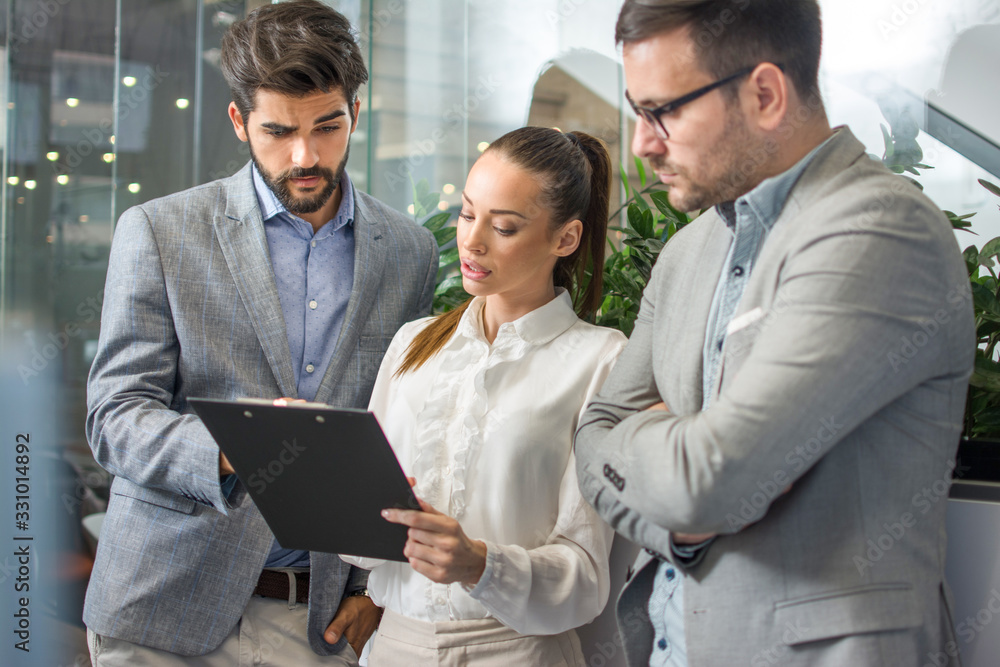 Beautiful businesswoman with male colleagues discussing about work in an office. Beautiful businesswoman with male colleagues discussing about work in an office.